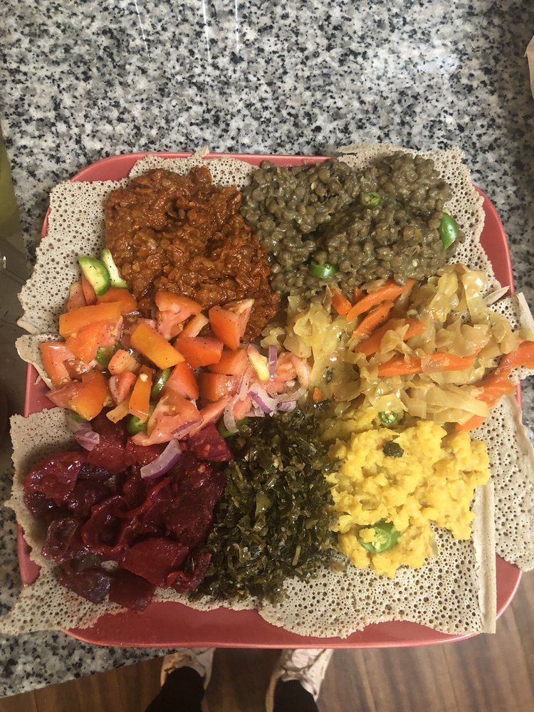Vegetarian combo platter on injera with lentils, greens, cabbage and salad