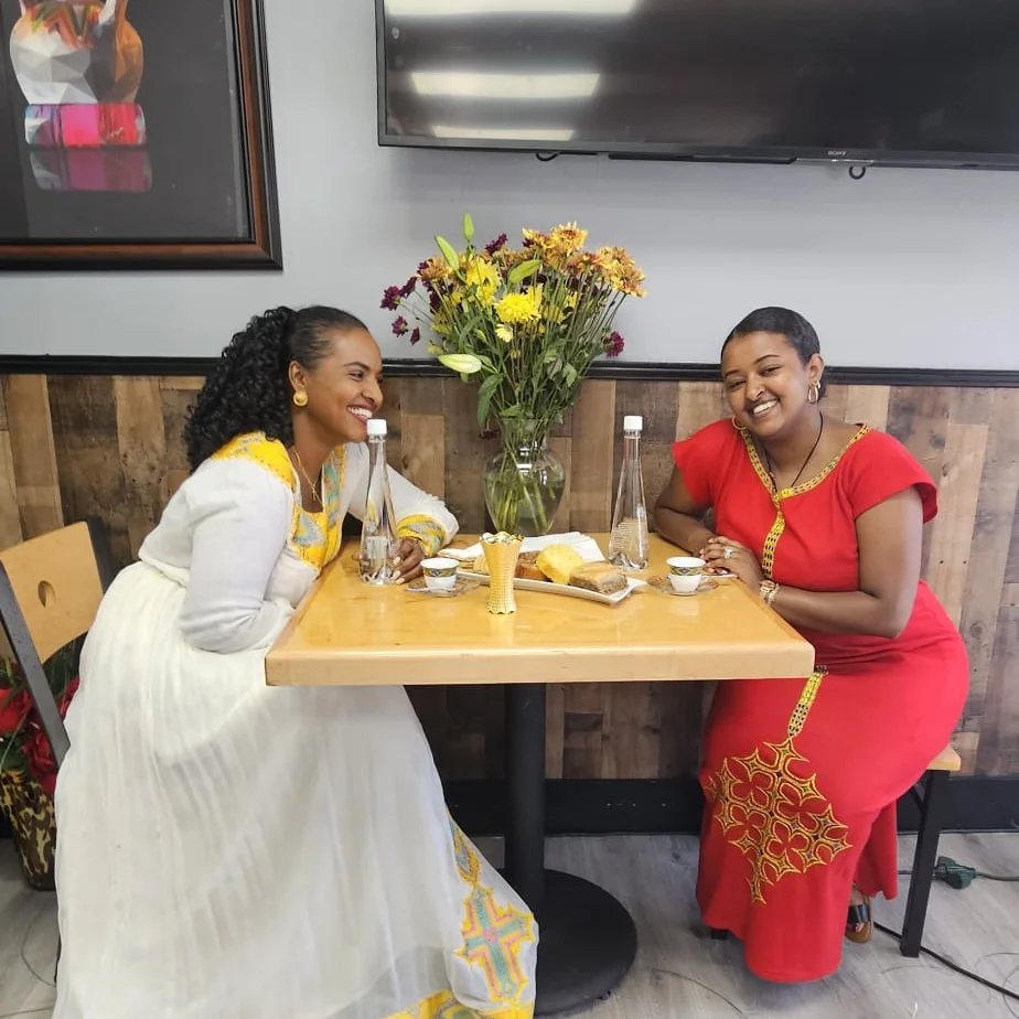 Two guests in traditional dress enjoying coffee at Eyoha
