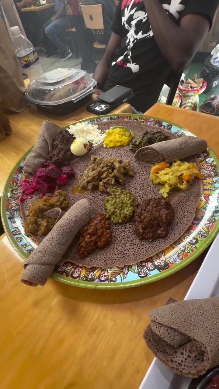 Combination platter with meat and vegetable stews on injera